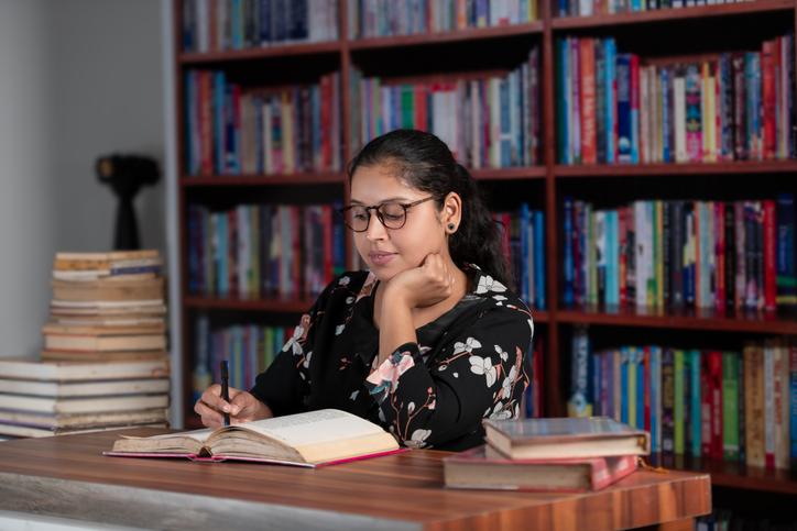 Young female student reading or studying in Library/iStock