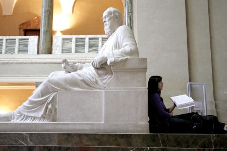 Female student leaning against statue