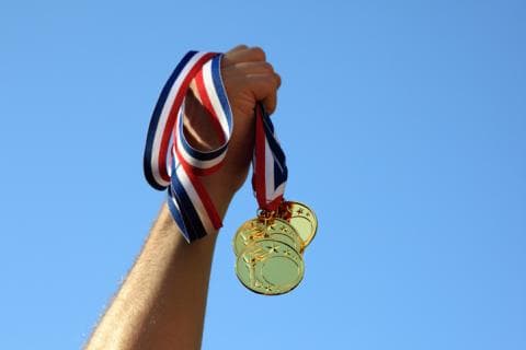 Hand holding three gold medals