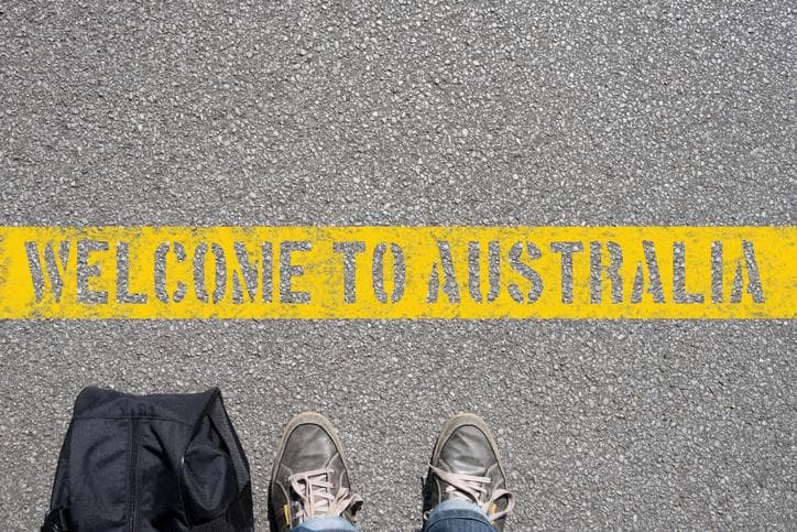 Man standing in front of a sign reading "Welcome to Australia"